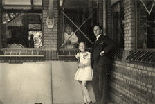 845160 Afbeelding van een vader en dochter tijdens een bezoek aan zijn zoon, achter een met plakstroken beschermd raam ...